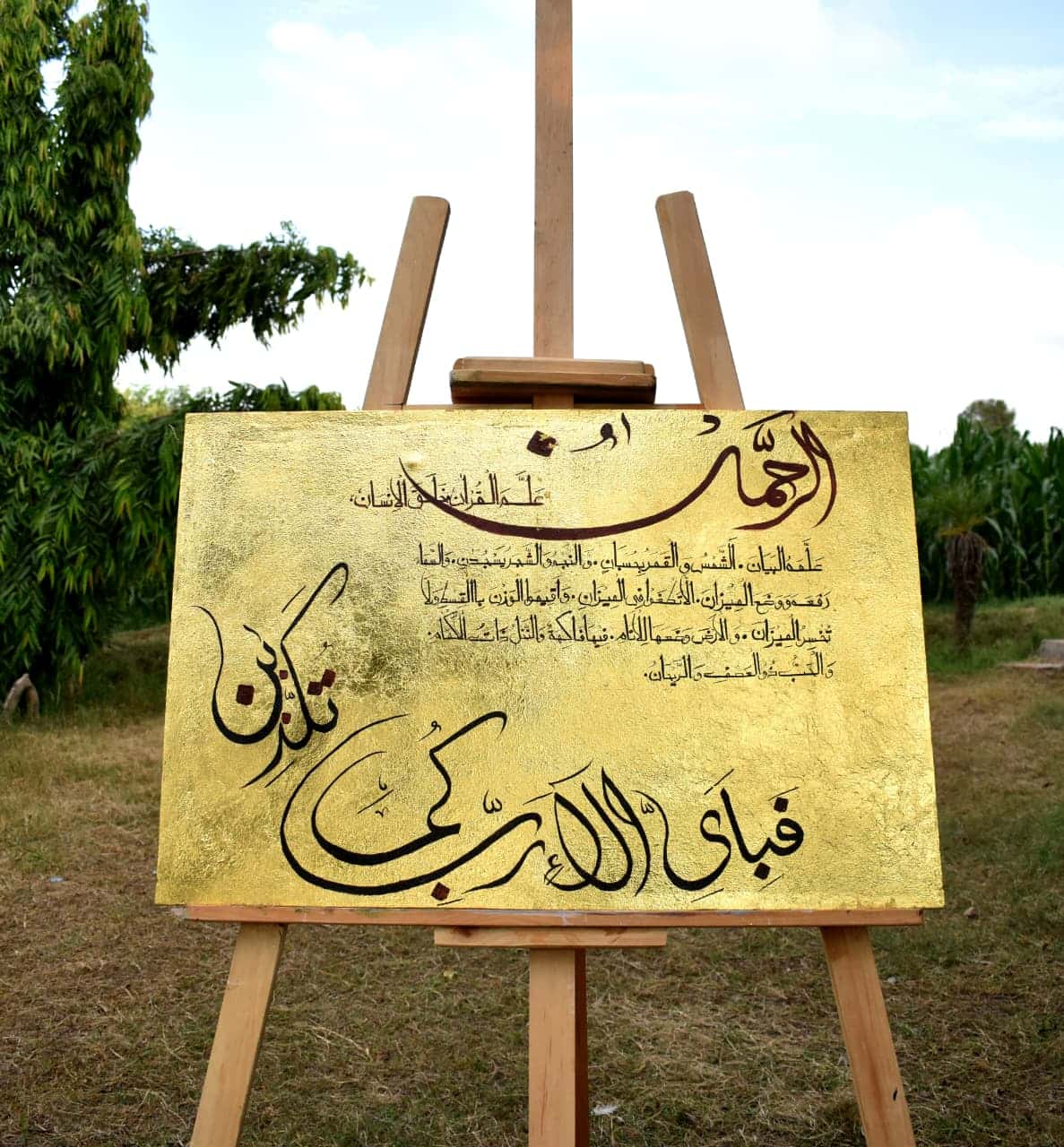 Gold Surah Rahman Islamic calligraphy painting with black Arabic script and burgundy accents on a landscape canvas